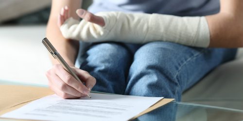 Disabled woman with bandaged arm signing document